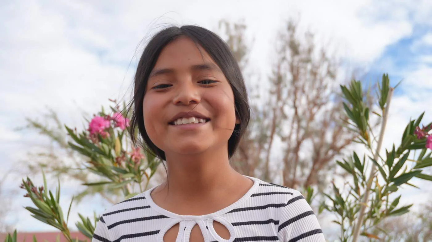 A girl from Toconao smiling among the flowers of the oasis
